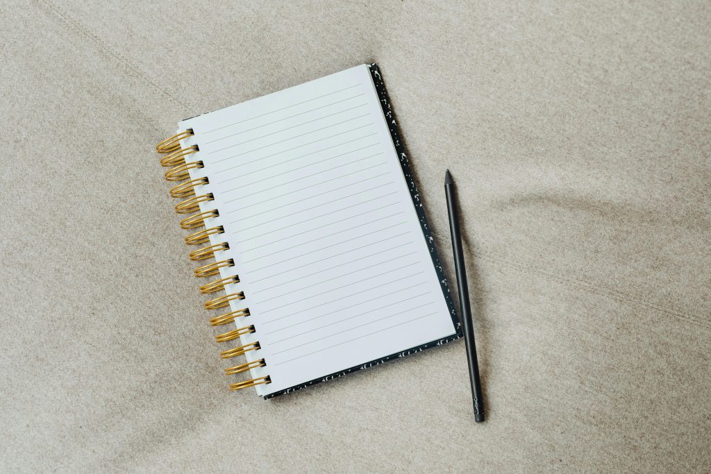 A minimalist notebook with a pencil on fabric surface, ideal for writing themes.